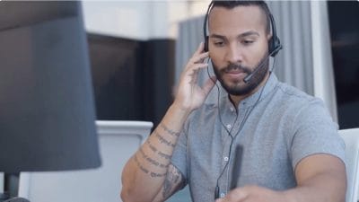 Man sitting by his desk while at work, wearing his headset.
